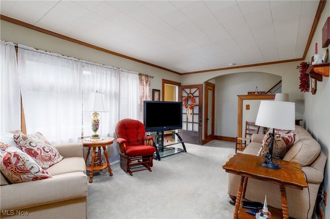 Carpeted living room with arched walkways, crown molding, and baseboards | Image 8