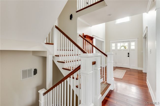 Entryway with visible vents, hardwood / wood-style flooring, baseboards, a towering ceiling, and stairway | Image 6