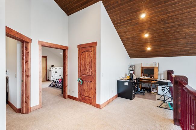 Carpeted office space featuring wooden ceiling, baseboards, high vaulted ceiling, and recessed lighting | Image 14