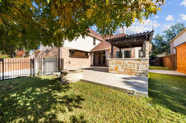 Rear view of house with a fenced backyard, a pergola, a patio, brick siding, and a chimney | Image 26