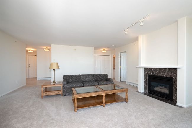 Living room with rail lighting, carpet floors, a fireplace, and a baseboard heating unit | Image 15