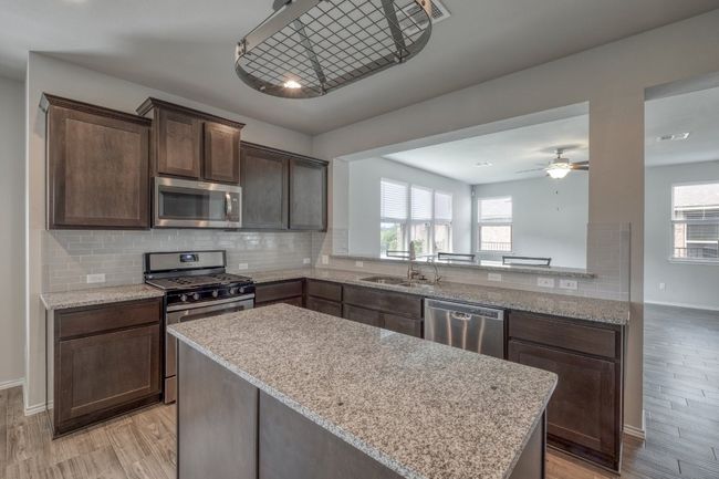 Kitchen with stainless steel appliances, light wood-style flooring, healthy amount of natural light, and dark brown cabinets | Image 8