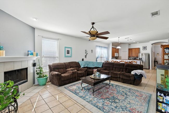 Living area featuring light tile patterned flooring, recessed lighting, ceiling fan, arched walkways, and a tile fireplace | Image 7