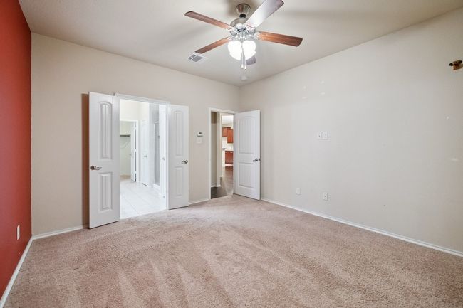 Unfurnished bedroom featuring light colored carpet, ceiling fan, and ensuite bath | Image 12