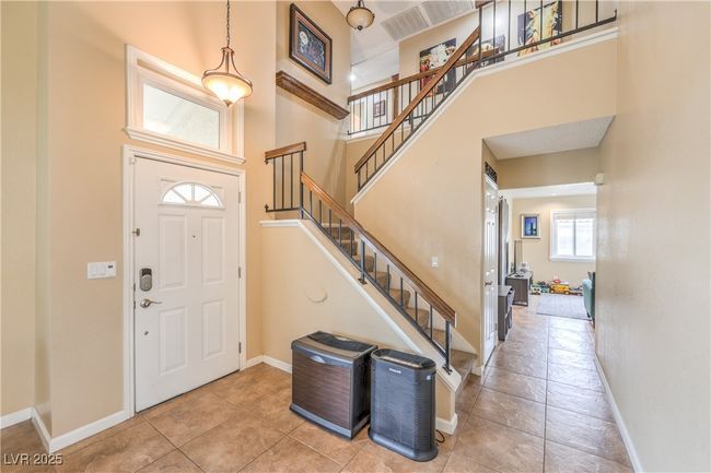 Tiled entryway featuring stairway, baseboards, and a towering ceiling | Image 9