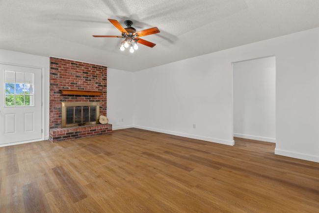 Unfurnished living room with wood finished floors, a ceiling fan, and a fireplace | Image 10
