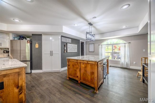 Kitchen featuring freestanding refrigerator, dark wood-type flooring, brown cabinets, light stone counters, and recessed lighting | Image 19