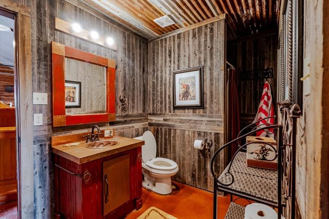 Bathroom with wood walls, vanity, finished concrete floors, and toilet | Image 20