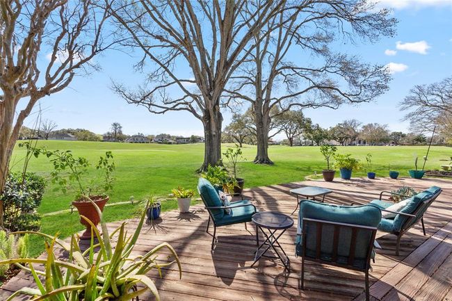 This spacious backyard deck offers stunning golf course views, creating a serene and picturesque setting. Surrounded by mature trees and lush greenery, the outdoor space provides the perfect spot for relaxation or entertaining. The wooden deck seamlessly blends with the natural landscape, while ample space allows for various seating arrangements to enjoy the peaceful surroundings. | Image 33