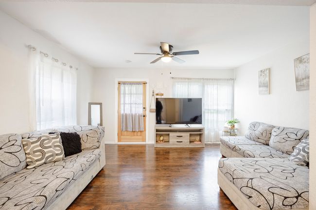 Living room featuring ceiling fan, baseboards, and dark wood-style floors | Image 5