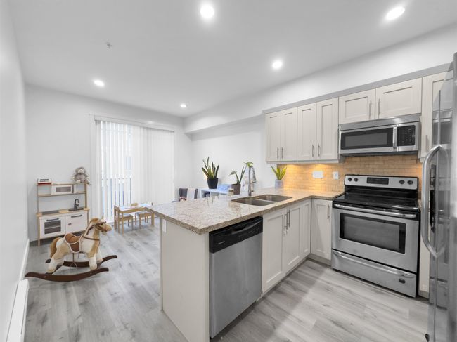 Kitchen featuring a sink, light wood-style floors, appliances with stainless steel finishes, a peninsula, and decorative backsplash | Image 6