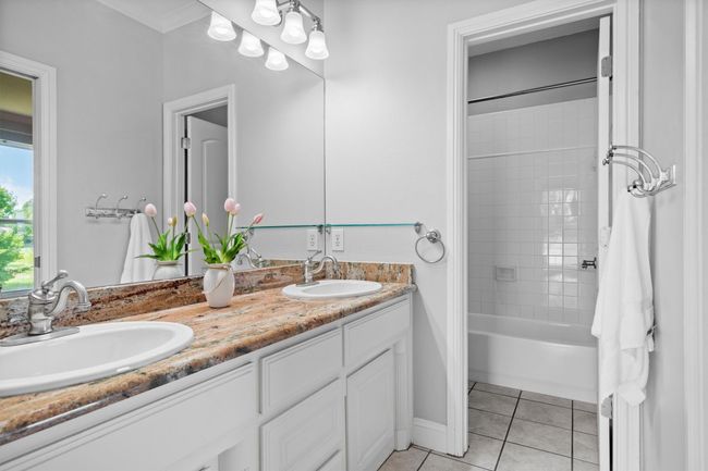 Guest bathroom with a secluded toilet space, a versatile shower-tub combo, and a generous double sink vanity area to accommodate multiple users. | Image 29