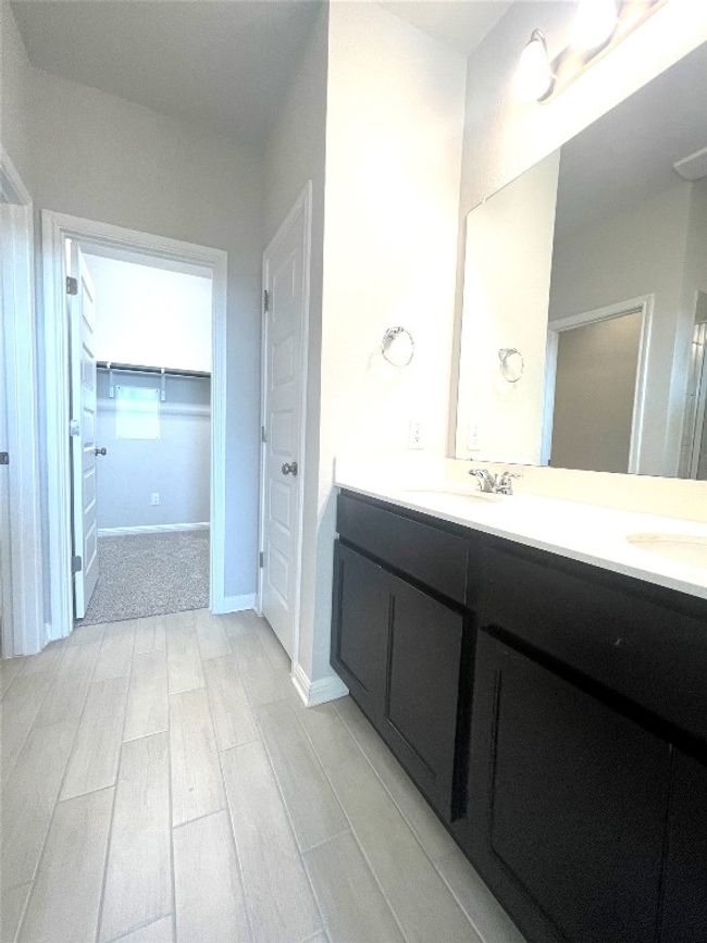 Bathroom featuring double vanity, wood tiled floors, and a walk in closet | Image 13
