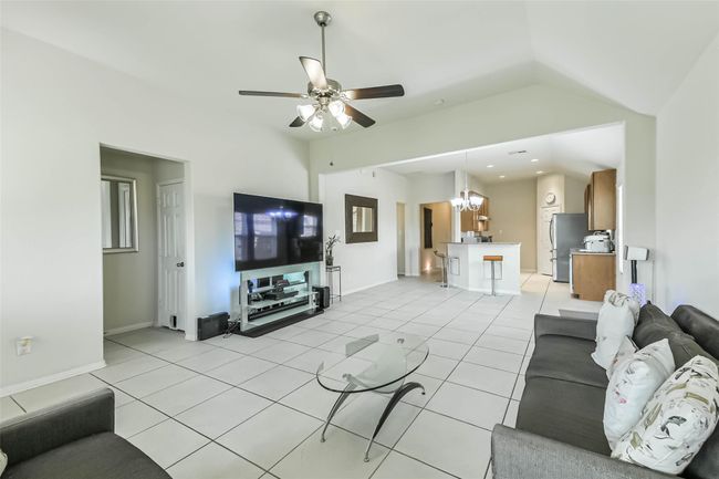This photo showcases the spacious, open concept living and kitchen area with high ceilings--adorned with a lovely modern ceiling fan. | Image 17
