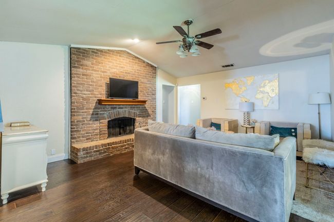 Living area featuring a ceiling fan, vaulted ceiling, hardwood / wood-style flooring, and a fireplace | Image 4