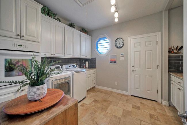 Laundry area with cabinet space, washing machine and clothes dryer, stone finish floor, and baseboards | Image 28
