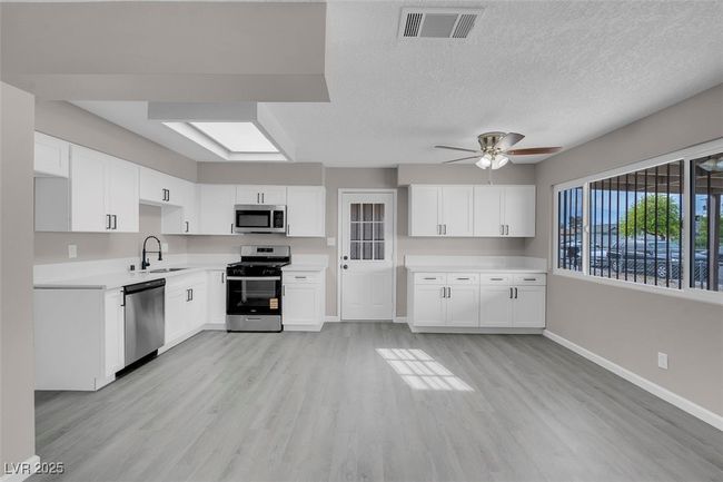 Kitchen with baseboards, stainless steel appliances, visible vents, and a sink | Image 11