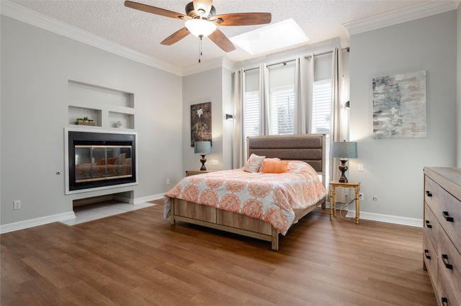 Bedroom with crown molding, baseboards, a textured ceiling, and wood finished floors | Image 18