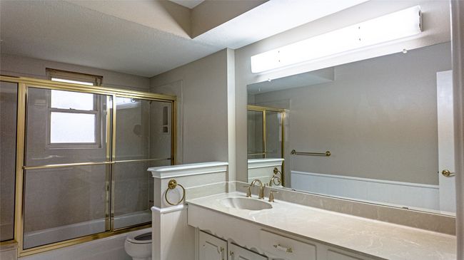 Bathroom with toilet, combined bath / shower with glass door, and vanity | Image 26