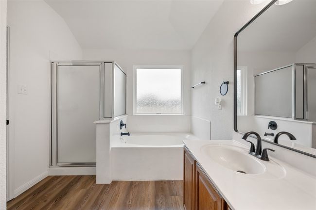 Full bath with a stall shower, wood finished floors, vanity, a bath, and vaulted ceiling | Image 28