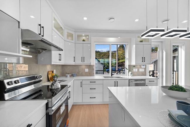 Kitchen with stainless steel appliances, extractor fan, decorative backsplash, white cabinetry, and glass insert cabinets | Image 8