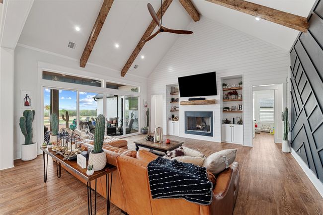 Living area featuring high vaulted ceiling, beam ceiling, a large fireplace, visible vents, and light wood-style floors | Image 16