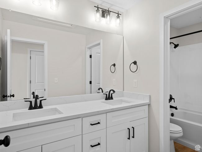 Full bath featuring double vanity, tub / shower combination, a sink, and toilet | Image 18