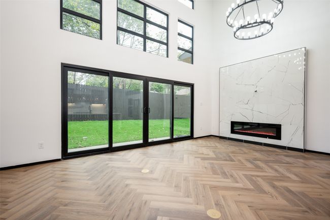 Unfurnished living room featuring a towering ceiling, a chandelier, and a premium fireplace | Image 12