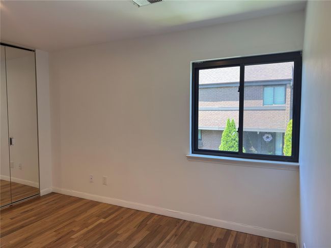 Unfurnished bedroom with baseboards, wood finished floors, multiple windows, and a closet | Image 19