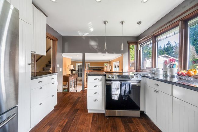 Kitchen featuring dark countertops, a peninsula, dark wood-style flooring, and appliances with stainless steel finishes | Image 8