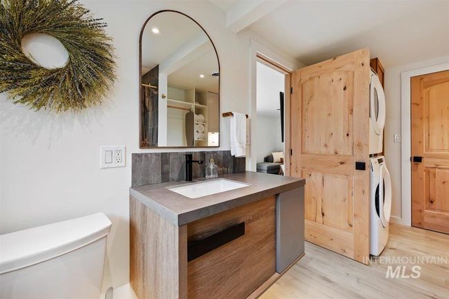 Full bathroom with stacked washer / drying machine, wood finished floors, vanity, decorative backsplash, and recessed lighting | Image 45