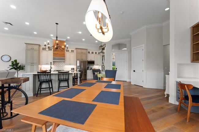 Dining area featuring a chandelier, wood finished floors, crown molding, recessed lighting, and a wainscoted wall | Image 11