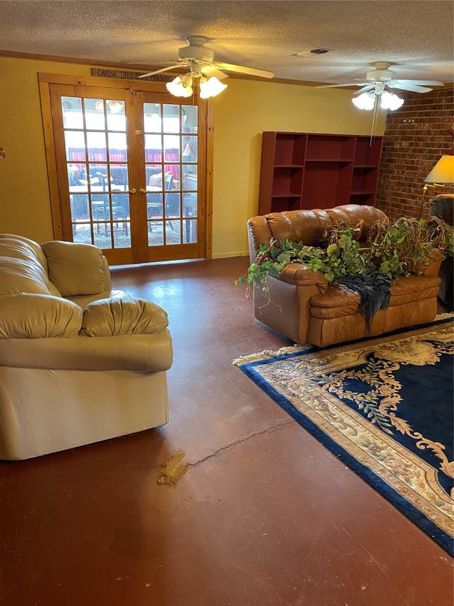 Living room featuring ceiling fan, concrete floors, and a textured ceiling | Image 11