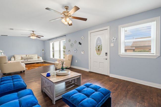 Living room with ceiling fan and dark wood-style floors | Image 6