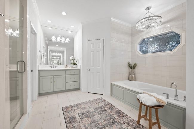 Bathroom featuring a chandelier, a bath, vanity, a shower stall, and ornamental molding | Image 17
