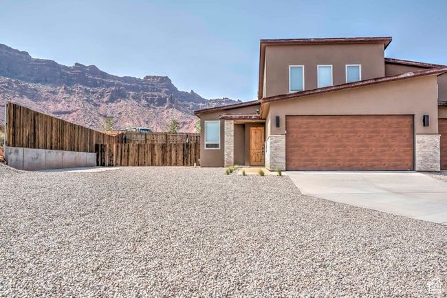 View of front of home with stucco siding, concrete driveway, a mountain view, stone siding, and an attached garage | Image 24