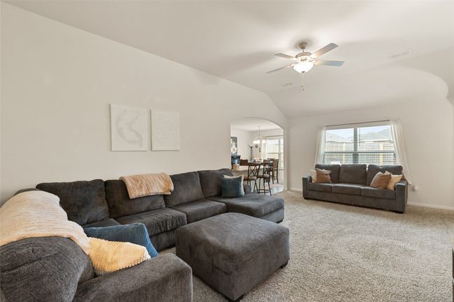 Living area with ceiling fan, arched walkways, carpet floors, and vaulted ceiling | Image 6