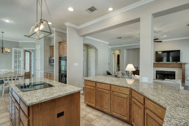 Kitchen with black appliances, open floor plan, a fireplace, a notable chandelier, and visible vents | Image 11