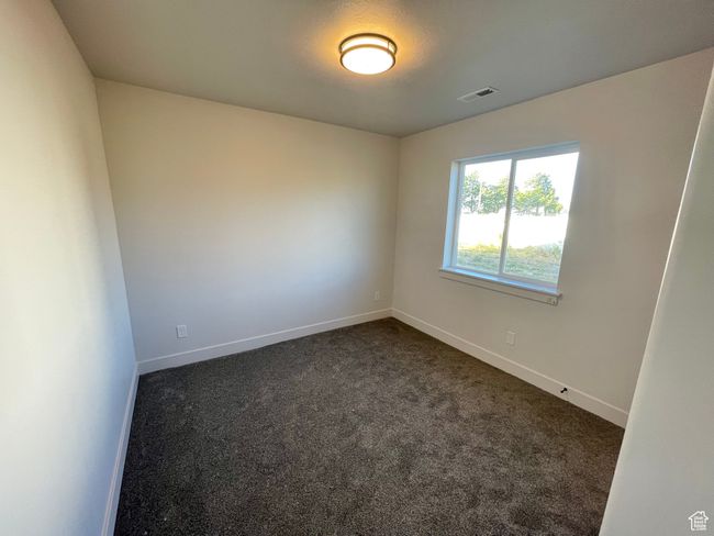 Empty room featuring dark colored carpet, visible vents, and baseboards | Image 12
