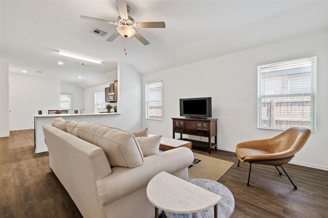 Living room with ceiling fan, dark wood-style flooring, and lofted ceiling | Image 6