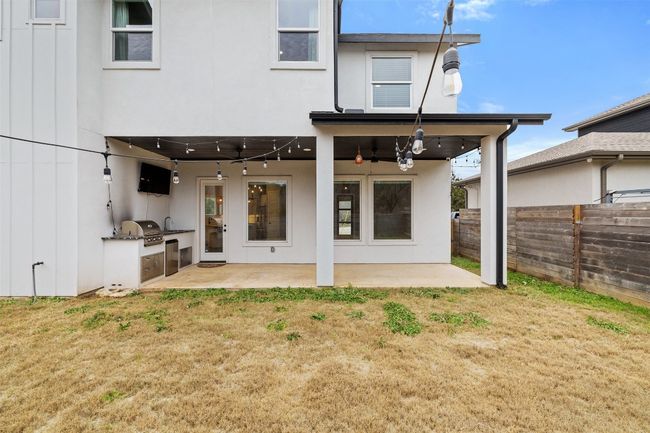 Back of property featuring ceiling fan, a patio area, an outdoor kitchen, and a lawn | Image 38