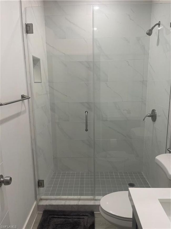 Bathroom featuring a shower with shower door, toilet, and vanity | Image 4