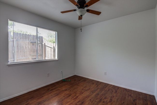 Empty room with dark wood-style flooring, baseboards, and ceiling fan | Image 15