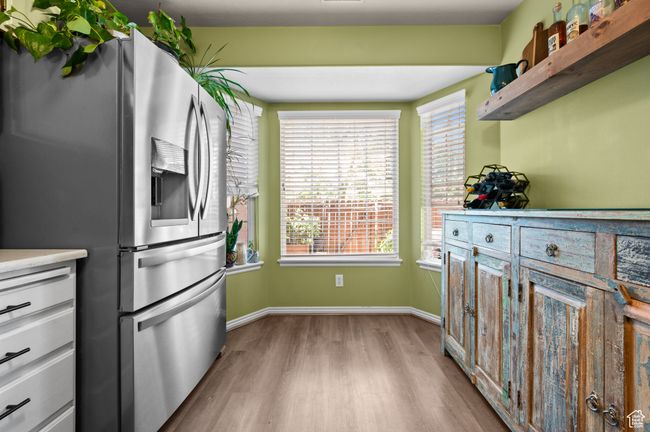 Kitchen with stainless steel fridge with ice dispenser, light wood-style flooring, light countertops, and open shelves | Image 12