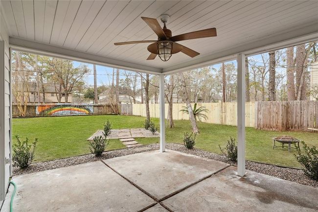 The covered patio with a ceiling fan, overlooks the oversized backyard. The yard includes a seating area and a fire pit, and there's a colorful mural on the back fence, adding a vibrant touch. Great for outdoor relaxation and entertaining. | Image 32