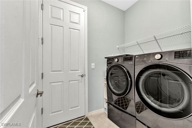 Clothes washing area with washer and clothes dryer, light tile patterned floors, laundry area, and baseboards | Image 25