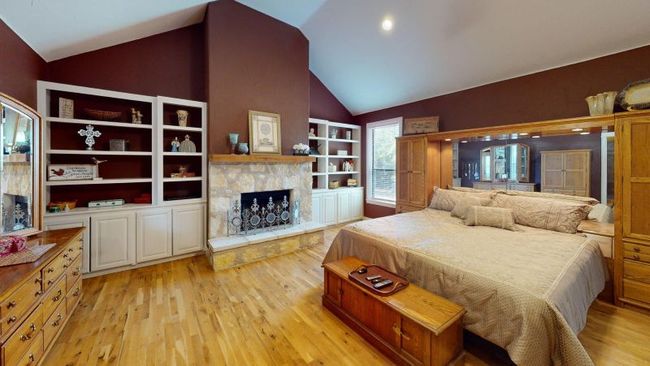 Bedroom with wood floors, lofted ceiling, and a fireplace | Image 12