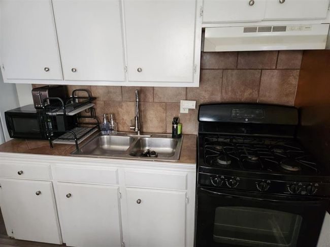 Modern kitchen in a cozy one-bedroom unit, featuring stylish cabinetry and a sleek gas stove. Perfect for culinary enthusiasts. | Image 22