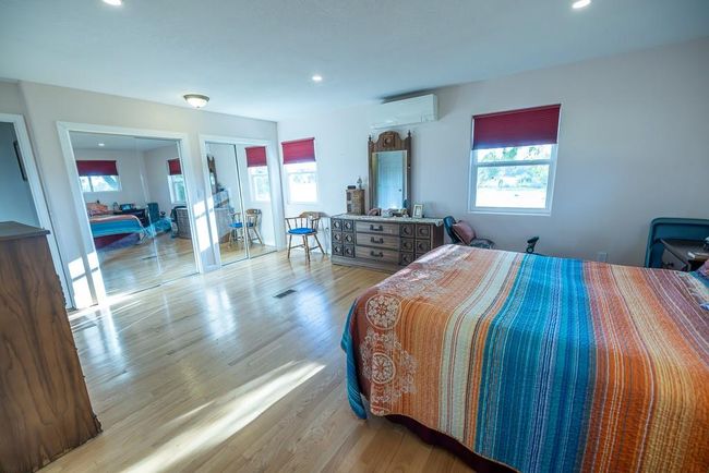 Bedroom with light wood-type flooring and an AC wall unit | Image 14