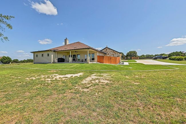Back of house with board and batten siding, ceiling fan, a patio area, and a chimney | Image 40